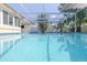 A screened in pool offers a refreshing oasis surrounded by lush tropical landscaping and comfortable seating at 1263 Overcash Dr, Dunedin, FL 34698