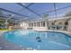 A screened pool is complemented by an adjacent patio area featuring outdoor seating and a hot tub at 1263 Overcash Dr, Dunedin, FL 34698