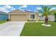 Charming single-story home with lush lawn, mature palm tree, and attached two-car garage at 12925 Fieldmoor Ct, Riverview, FL 33579