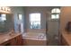 Bathroom featuring dual sinks, a soaking tub below a bright window, and a glass enclosed shower at 16515 Nikki Ln, Odessa, FL 33556