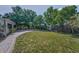 Spacious backyard with a brick path, lush greenery, and a mix of chain link and vinyl fencing at 1766 Hitching Post Ln, Dunedin, FL 34698