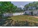 Well-maintained backyard featuring green lawn, mature trees, and a white vinyl fence for added privacy at 1766 Hitching Post Ln, Dunedin, FL 34698