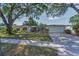 Inviting one-story home with an attached garage, complemented by a green lawn and mature trees at 1766 Hitching Post Ln, Dunedin, FL 34698