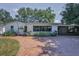 Charming home featuring a brick driveway, lush landscaping, and a welcoming screened-in porch at 1766 Hitching Post Ln, Dunedin, FL 34698