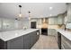 Well-lit kitchen features an island with seating, stainless appliances, neutral cabinets, and stylish pendant lights at 1766 Hitching Post Ln, Dunedin, FL 34698
