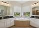 Elegant bathroom featuring dual vanities, granite countertops, and a large jacuzzi tub at 19803 Prince Benjamin Dr, Lutz, FL 33549