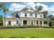 Elegant two-story home showcasing a covered front porch, manicured lawn, and a charming water fountain at 19803 Prince Benjamin Dr, Lutz, FL 33549