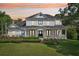 Stately two-story home at sunset showcasing a charming wrap-around porch and meticulous landscaping at 19803 Prince Benjamin Dr, Lutz, FL 33549