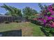 Well-kept backyard with mature landscaping, a wooden fence, and vibrant bougainvillea at 2212 Portside Psge, Palm Harbor, FL 34685