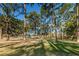 Expansive grassy lawn with mature trees offering shade and a glimpse of a house in the background on a sunny day at 2212 Portside Psge, Palm Harbor, FL 34685