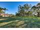 Expansive grassy lawn with mature trees shading the area with a view of the community buildings in the distance at 2212 Portside Psge, Palm Harbor, FL 34685
