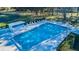 Aerial view of a community pool with ample seating including lounge chairs and patio tables at 2212 Portside Psge, Palm Harbor, FL 34685