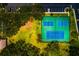 A top-down view of a tennis court featuring a green surface and blue lines, surrounded by trees and parking at 255 114Th N Ave # 4, St Petersburg, FL 33716