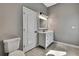 Cozy bathroom featuring a toilet, sink, a white cabinet, marble countertops, and a modern light fixture at 27338 Elkwood Cir, Wesley Chapel, FL 33544