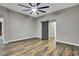Spacious bedroom featuring hard wood floors, a ceiling fan, and a gray barn door leading to the en-suite bathroom at 27338 Elkwood Cir, Wesley Chapel, FL 33544