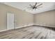 Well-lit bedroom showcasing wood-look floors, a stylish ceiling fan, and neutral decor with a door for entry at 27338 Elkwood Cir, Wesley Chapel, FL 33544