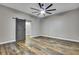 Bedroom featuring hard wood floors, a ceiling fan, and a gray barn door leading to the closet at 27338 Elkwood Cir, Wesley Chapel, FL 33544