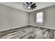 Bedroom features a ceiling fan, wood-look flooring, neutral paint, and a window with natural light at 27338 Elkwood Cir, Wesley Chapel, FL 33544