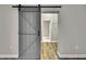 Bedroom featuring hard wood floors and a gray barn door leading to the walk-in closet at 27338 Elkwood Cir, Wesley Chapel, FL 33544