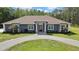 Charming single-story home with a circle driveway, a well-kept lawn, gray siding and a decorative front door at 27338 Elkwood Cir, Wesley Chapel, FL 33544