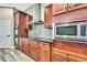 Close-up of a kitchen featuring stainless steel microwave and oven, dark wood cabinets, and mosaic tile backsplash at 27338 Elkwood Cir, Wesley Chapel, FL 33544