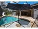 Screened pool with a slide, waterfall feature, and umbrella surrounded by beautiful landscaping at 27338 Elkwood Cir, Wesley Chapel, FL 33544