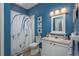 Well-lit bathroom with blue accents, shower, vanity, and decorative floral shower curtain at 2747 Wood Pointe Dr, Holiday, FL 34691