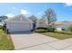 Inviting home with a well-manicured lawn, mature trees, and a spacious driveway leading to a two-car garage at 2747 Wood Pointe Dr, Holiday, FL 34691