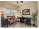 Bright office with a black desk and chair, grey loveseat with colorful pillows, and wood-look floors at 2747 Wood Pointe Dr, Holiday, FL 34691
