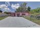 Charming pink one-story home featuring a covered carport, manicured lawn, and mature landscaping at 3104 W Powhatan Ave, Tampa, FL 33614