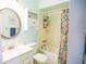 Cozy bathroom featuring a tub with a colorful shower curtain and round mirror at 3139 W Varn Ave, Tampa, FL 33611