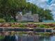 Attractive neighborhood entrance with stone features, landscaping, and a serene pond reflecting the sky at 3909 Valrico Grove Dr, Valrico, FL 33594