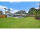 Spacious backyard view with green grass, privacy fence and in-ground pool with a screened in lanai attached to the home at 4230 Indianapolis Ne St, St Petersburg, FL 33703