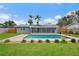Backyard view of a light blue home with solar panels, screened in lanai and a bright blue in-ground pool at 4230 Indianapolis Ne St, St Petersburg, FL 33703
