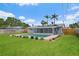 A backyard view of a light blue home with solar panels, screened in lanai and a bright blue in-ground pool at 4230 Indianapolis Ne St, St Petersburg, FL 33703