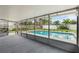 View of the screened in lanai with a bright blue in-ground pool surrounded by green grass and well kept fences at 4230 Indianapolis Ne St, St Petersburg, FL 33703