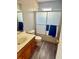 Bathroom featuring a shower-tub combo with glass doors, wood-look flooring and a vanity at 439 Corbett Rd, Lithia, FL 33547