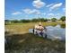 A girl riding a horse in a large grassy pond, next to other horses and buildings at 439 Corbett Rd, Lithia, FL 33547