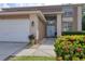 Inviting home exterior with a two-car garage, charming blue double doors, and colorful landscaping at 4750 Augusta Ave, Oldsmar, FL 34677