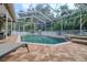 Enclosed pool area featuring brick pavers, lounge chairs and a pristine pool surrounded by lush landscaping at 4750 Augusta Ave, Oldsmar, FL 34677