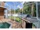 Outdoor kitchen area in the screened-in pool area featuring a stainless steel grill and lush backyard at 4750 Augusta Ave, Oldsmar, FL 34677
