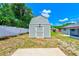 A gray barn-style storage shed with a door and gray shingle roof in the backyard at 521 E Lumsden Rd, Brandon, FL 33511