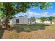 View of the backyard featuring a white home exterior, green grass, and a large tree at 622 Cedar Grove Dr, Brandon, FL 33511