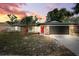 Charming single-story home with stone accents, a red door, fresh landscaping, and a dark garage door at 622 Cedar Grove Dr, Brandon, FL 33511