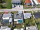 Aerial view of home shows gray roof, fenced in yard, inground screened pool, and painted driveway at 6240 Keller Dr, Port Richey, FL 34668