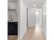 Hallway with kitchen access and bathroom, enhanced with a light wood floor at 6240 Keller Dr, Port Richey, FL 34668