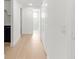 Hallway with light wood floors leading to a bright bathroom with marble shower at 6240 Keller Dr, Port Richey, FL 34668
