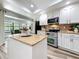 Bright kitchen featuring an island, granite countertops, stainless appliances, and white cabinetry at 66 Bay Woods Dr, Safety Harbor, FL 34695