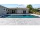 Backyard featuring an in-ground pool, gray stone patio, and the home's exterior, all surrounded by lush greenery at 715 39Th Ne Ave, St Petersburg, FL 33703