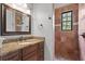Bathroom featuring granite counters, dark wood cabinets, framed mirror, and tiled shower with a window at 7713 Still Lakes Dr, Odessa, FL 33556
